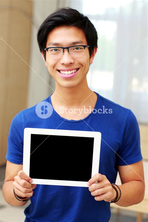 Young Smiling Asian Man Showing Blank Tablet Computer Screen At Home