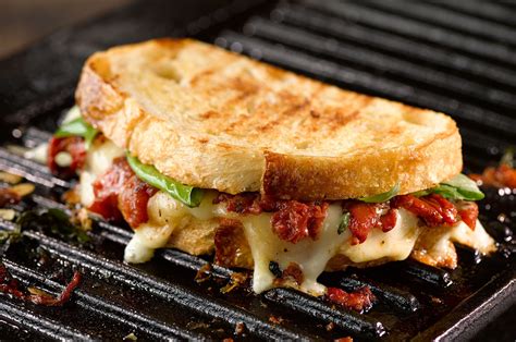 Grilled Cheese Sandwich Oozing With Melted Cheese Roasted Tomato And Basil Leaves Shown On A
