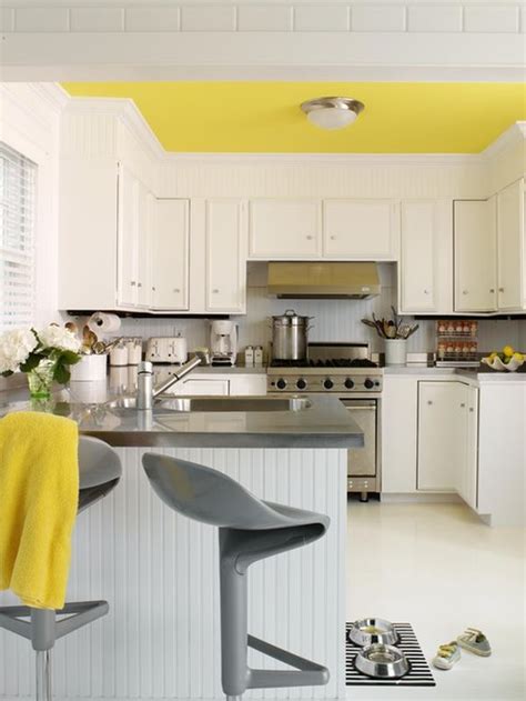 A contemporary kitchen with white cabinets, a bright yellow tile backsplash and a lamp, white chairs and neutrals. Decorating Yellow & Grey Kitchens: Ideas & Inspiration