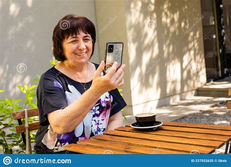 Den äldre Kvinnan Har Videochatt Med Vänner I Ett Kafé Fotografering för Bildbyråer Bild av