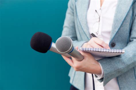 news reporter or tv journalist at press conference holding microphone and writing notes