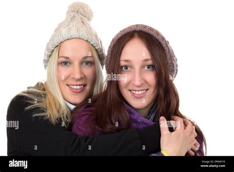 Two Young Women In Winter Clothing Hug Each Other Isolated On A White