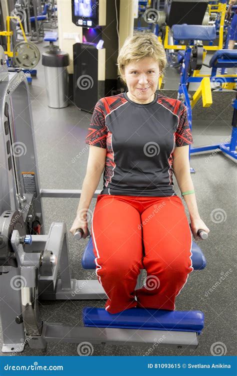 Mature Woman Doing Seated Leg Curl In Exercise Machine During Fitness Workout In The Gym Stock