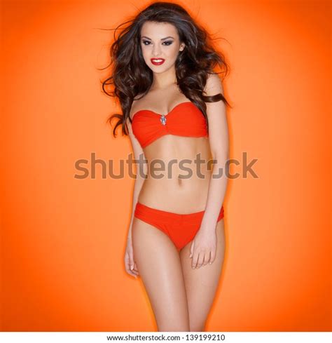 Sexy Girl In Red Bikini Posing On Orange Background
