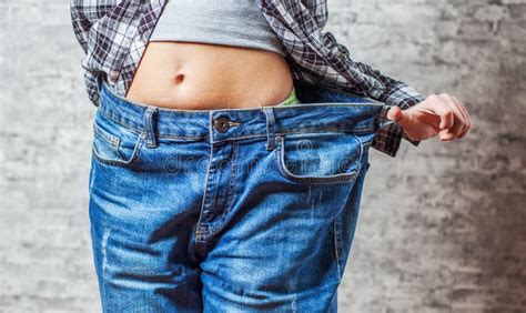 Woman Shows Her Weight Loss By Wearing An Old Jeans On Gray Wall Background Stock Image Image