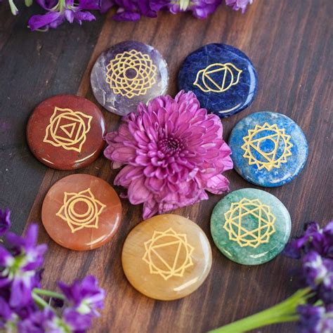 Seven Chakra Stones With Gold Lines On Them And Purple Flowers In The