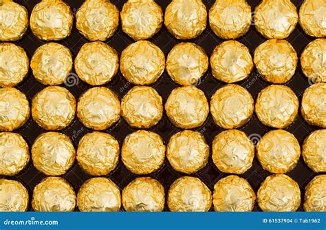 Box Of Candies Wrapped In Bright Golden Foil Wrappers Stock Photo