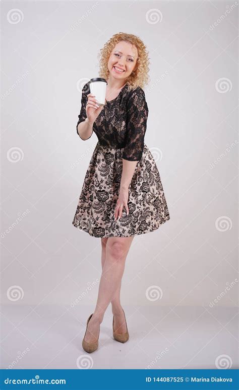 Cute Curly Blonde Girl Stands In Lace Short Evening Dress And Holds A