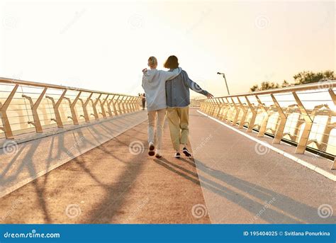 Full Length Shot Of Lesbian Couple Hugging Walking On The Bridge And Watching The Sunrise