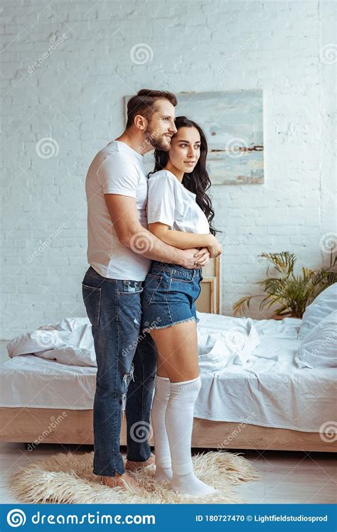 Handsome Man In Jeans Hugging Beautiful And Brunette Woman In T Shirt