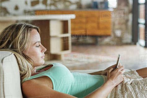 Woman Laying On Sofa And Texting With Cell Phone Stock Photo Dissolve