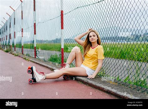 Pretty Cheerful Teen Girl Wearing Shorts With Roller Skates And Sitting
