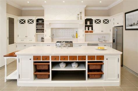 A white kitchen island is fitted with a marble countertop and a set of low back wicker island stools under four white drum light pendants. Shelves with Baskets - with Hooks and for Storage | Founterior