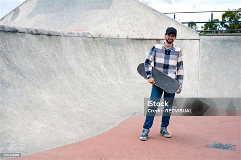 밀레니엄 세대 스케이트 보더가 스케이트 보드를 들고 스케이트 파크에서 카메라를 바라 보는 초상화 20 29세에 대한 스톡 사진 및 기타 이미지 Istock