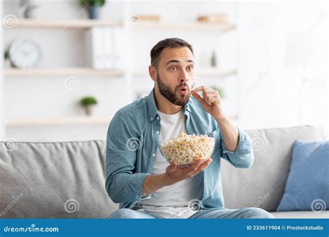Millennial Caucasian Man Eating Popcorn While Watching Tv At Home
