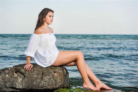Caucasian Teen Girl In Bikini And White Shirt Lounging On Lava Rocks By The Ocean Stock Image
