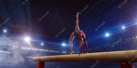 premium photo female gymnast doing a complicated trick on gymnastics balance beam in a