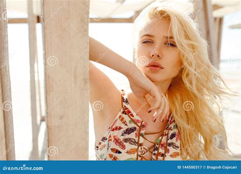 Blonde With Curly Hairblue Eyesbig Lips Supported On A Wooden Building And Sensual Looking At