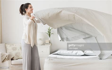 Usa New Jersey Jersey City Woman Spreading Sheet On Bed Photo Getty