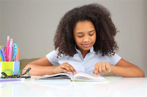 Premium Photo Dark Skinned Schoolgirl Reading A Book Doing Homework
