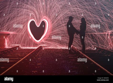Silhouette Of Man And Woman With Sparks Behind Them In A Love Heart