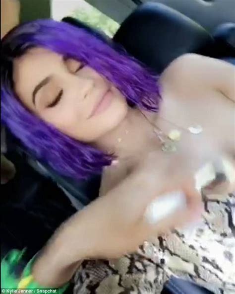 A Woman With Purple Hair Sitting In The Back Seat Of A Car And Holding Her Hand Out