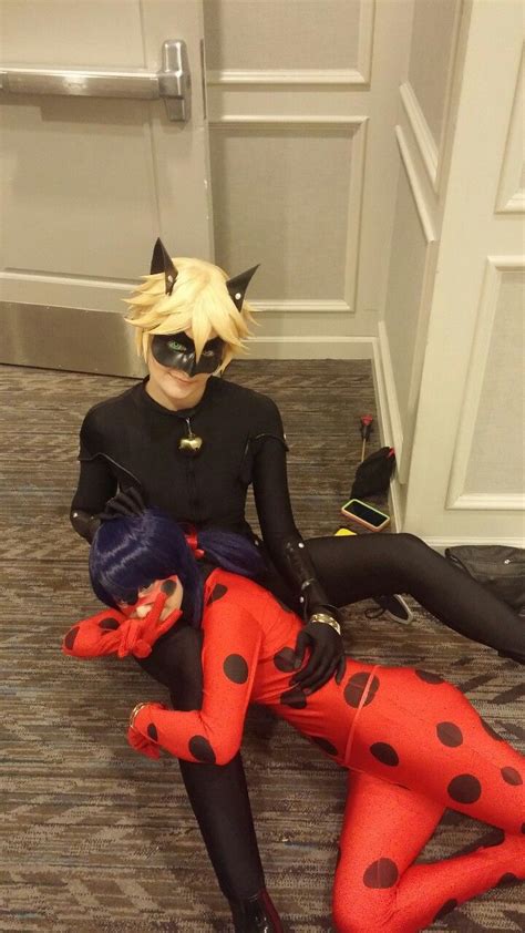 Two People Dressed Up As Ladybug And Catwoman Sitting On The Floor