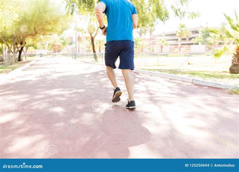 Jogger Training On Footpath During Sunny Day In Park Stock Photo