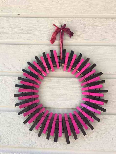 A Pink And Black Wreath Hanging On The Side Of A White Wooden Wall Next