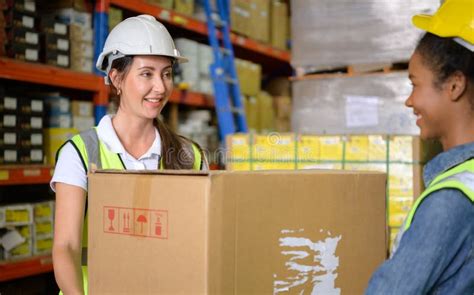 Two Girls Warehouse Workers Help Each Other Lift Heavy Boxes Stock Image Image Of Delivery