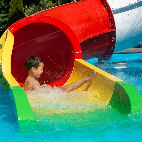 Happy Cheerful Boy Splashing Water On Water Slide At Aqua Park Stock