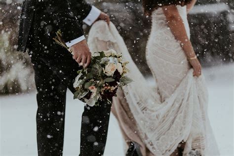 The Bride And Groom Are Standing In The Snow Holding Each Others Bouquets