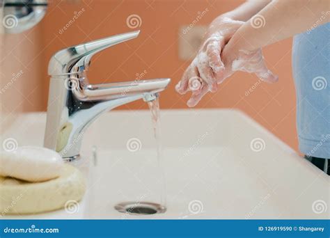 A Little Boy Washes His Hands With Soap In The Bathroom Stock Photo