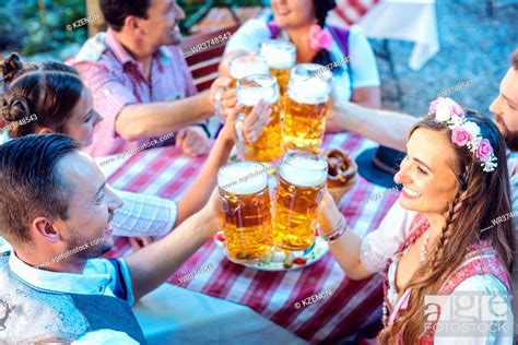 People Enjoying Food And Drink In Bavarian Beer Garden On A Sunny Day