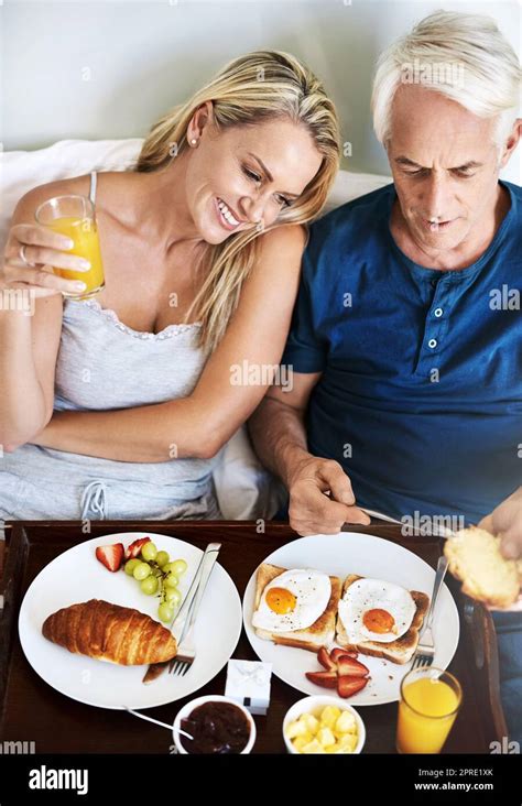 Waking Up To The Perfect Day Together An Affectionate Mature Couple Enjoying Breakfast In Bed