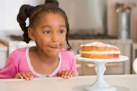 Girl Staring Longingly At Cake At Home Licking Lips Stock Image
