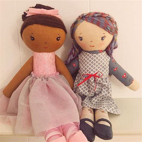 Two Dolls Sitting Next To Each Other On Top Of A Shelf In Front Of A Wall