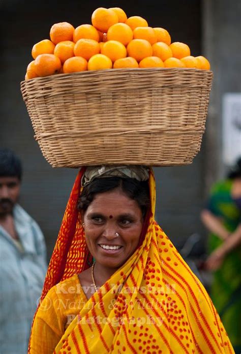 indian woman carrying a basket of oranges on her head to markets we are the world people around