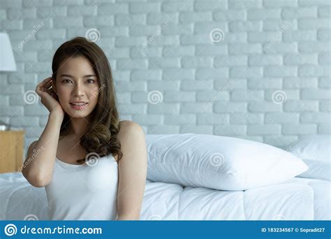 asian woman cheerful and healthy and wearing white pajamas wake up on bed in bedroom in the