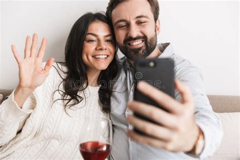 Image Of Caucasian Couple Taking Selfie Photo Together On Sofa While Drinking Wine In Bright
