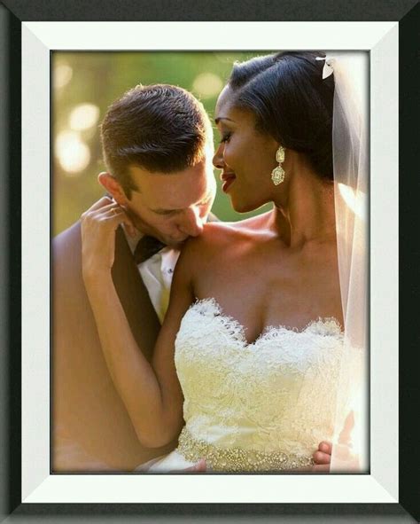 A Bride And Groom Pose For A Wedding Photo In Front Of The Camera With Their Arms Around Each Other