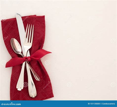 fancy christmas or valentines day table place setting with cloth red napkin silverware and bow