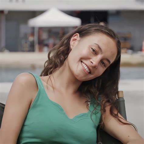 A Woman With Long Brown Hair And Green Shirt Smiling At The Camera