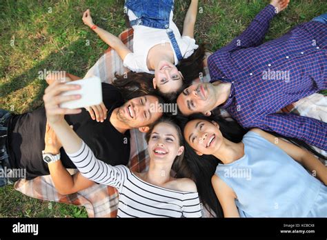 Happy Young Friends Lying On Grass And Taking Selfie Top View Portrait