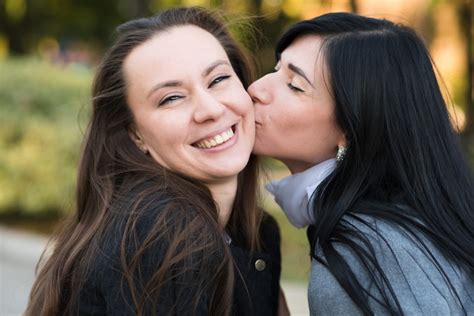 premium photo happy lesbian caucasian couple kissing on the cheek standing in the park in