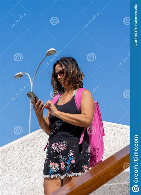 Beautiful Middle Aged Female Tourist Using Smartphone While Walking