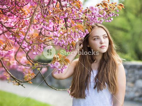 Beautiful Girl In Spring Garden Among The Blooming Trees With Pink