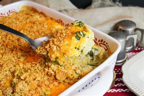 A Casserole Dish With Broccoli And Cheese Being Scooped From The Casserole