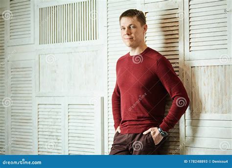 Young Handsome Man Stands Leaning Against Wall His Hands In His Pocket