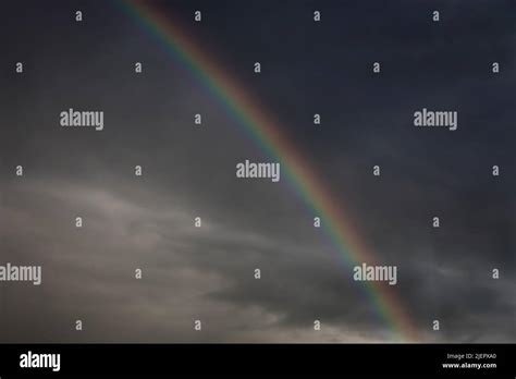 rainbow after a summer thunderstorm and rain in a dark sky Stock Photo